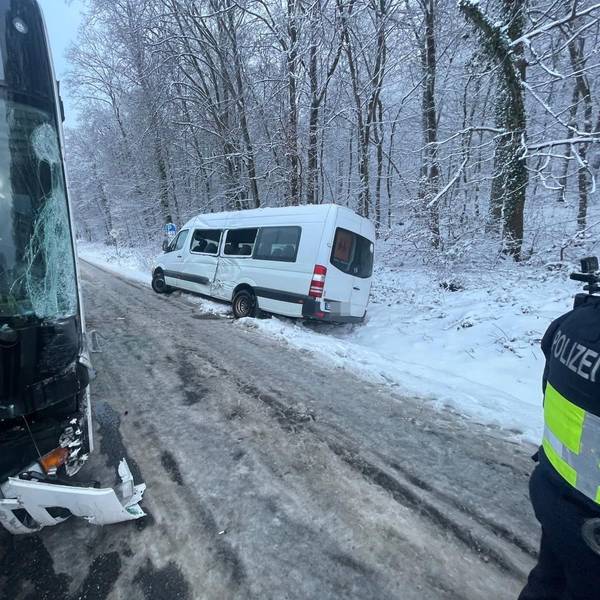 Ein weißer Kleinbus steht in einem verschneiten Straßengraben.