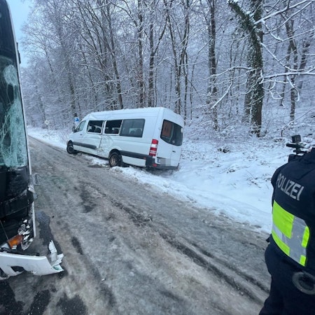 Ein weißer Kleinbus steht in einem verschneiten Straßengraben.