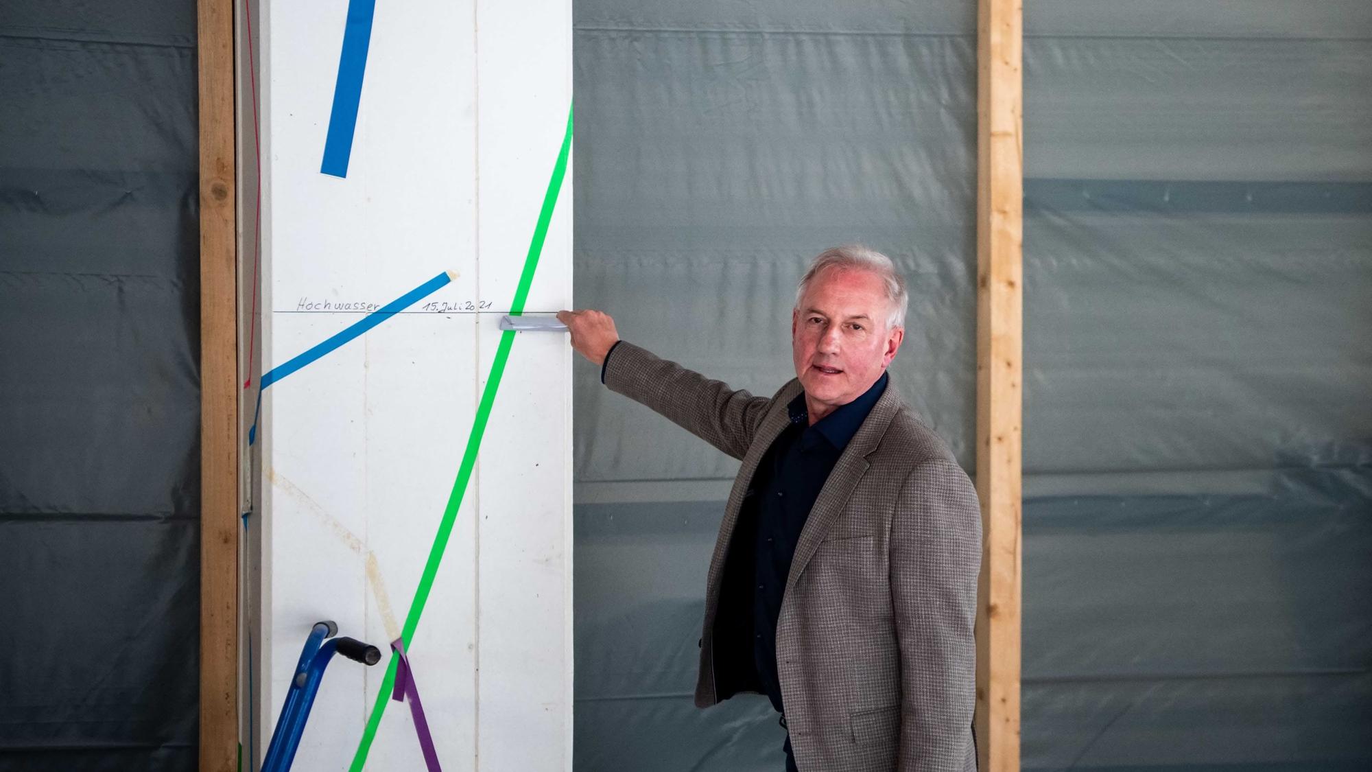Schulleiter Wolfgang Schmitz zeigt mit der Hand auf eine Flutmarke.