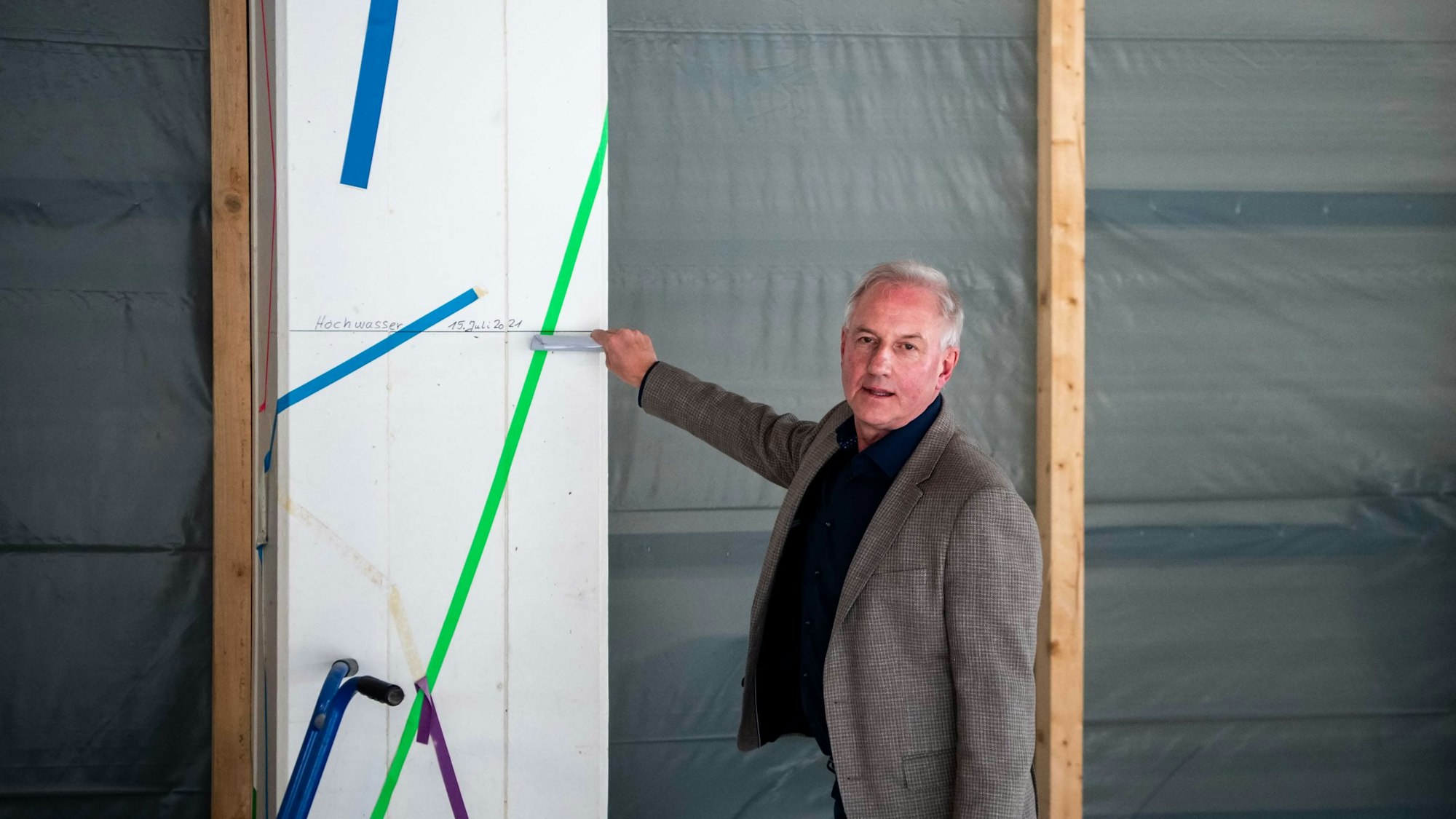 Schulleiter Wolfgang Schmitz zeigt mit der Hand auf eine Flutmarke.