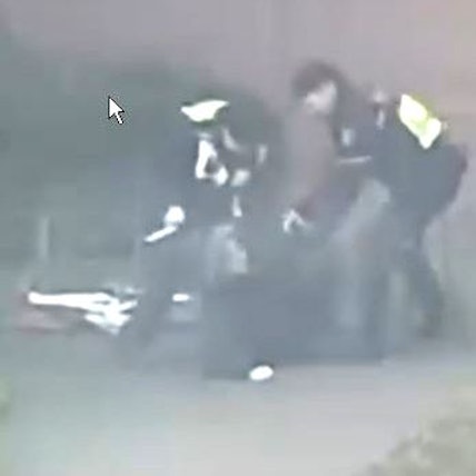 Das Bild ist ein Ausschnitt aus einer Videoaufnahme und zeigt zwei Polizisten, die auf eine Person einschlagen.