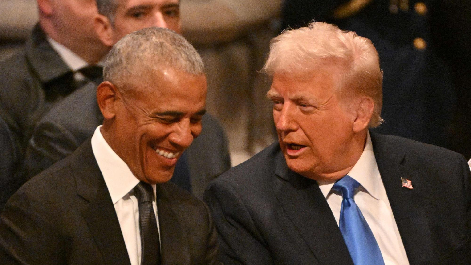 Während die meisten Gäste vor der Gedenkfeier still auf ihrem Platz saßen, lachten Barack Obama und Donald Trump während ihres Gesprächs kurz.