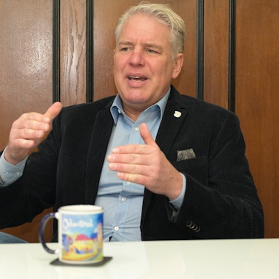 Bürgermeister Robert Lennerts sitzt in seinem Amtszimmer am Tisch und spricht gestikulierend.