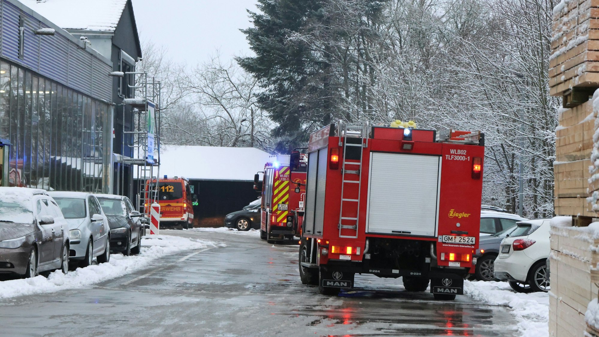 Eine Einsatzkraft der Feuerwehr steht neben einem Einsatzfahrzeug der Feuerwehr.