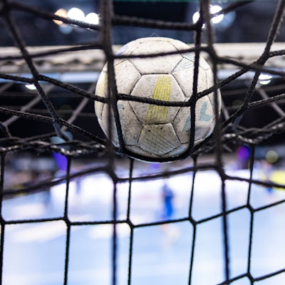 Ein Handball im Netz eines Tores.