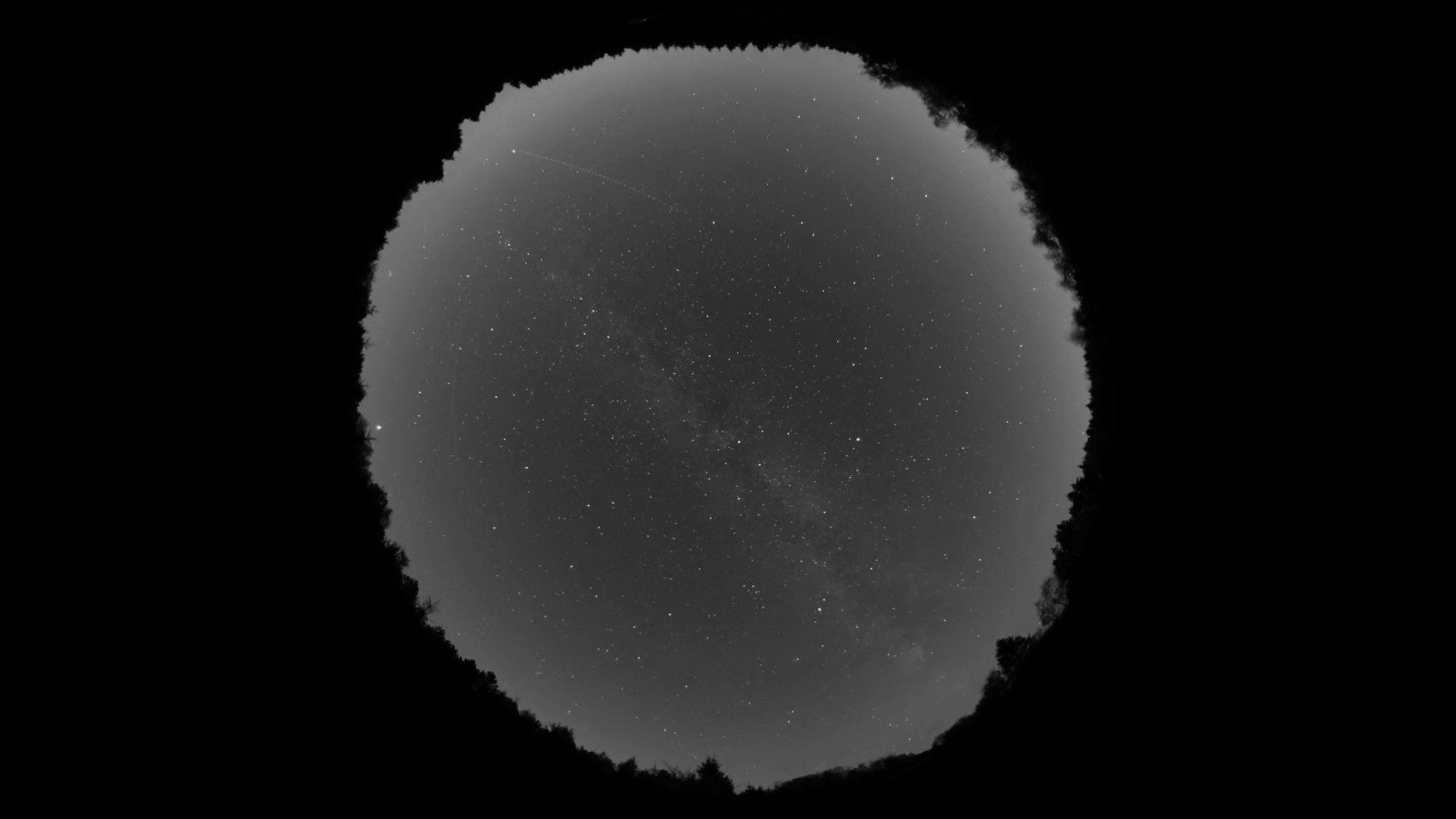 Das Bild zeigt ein Foto eines Sternenhimmels. An den Rändern wird der Himmel heller.