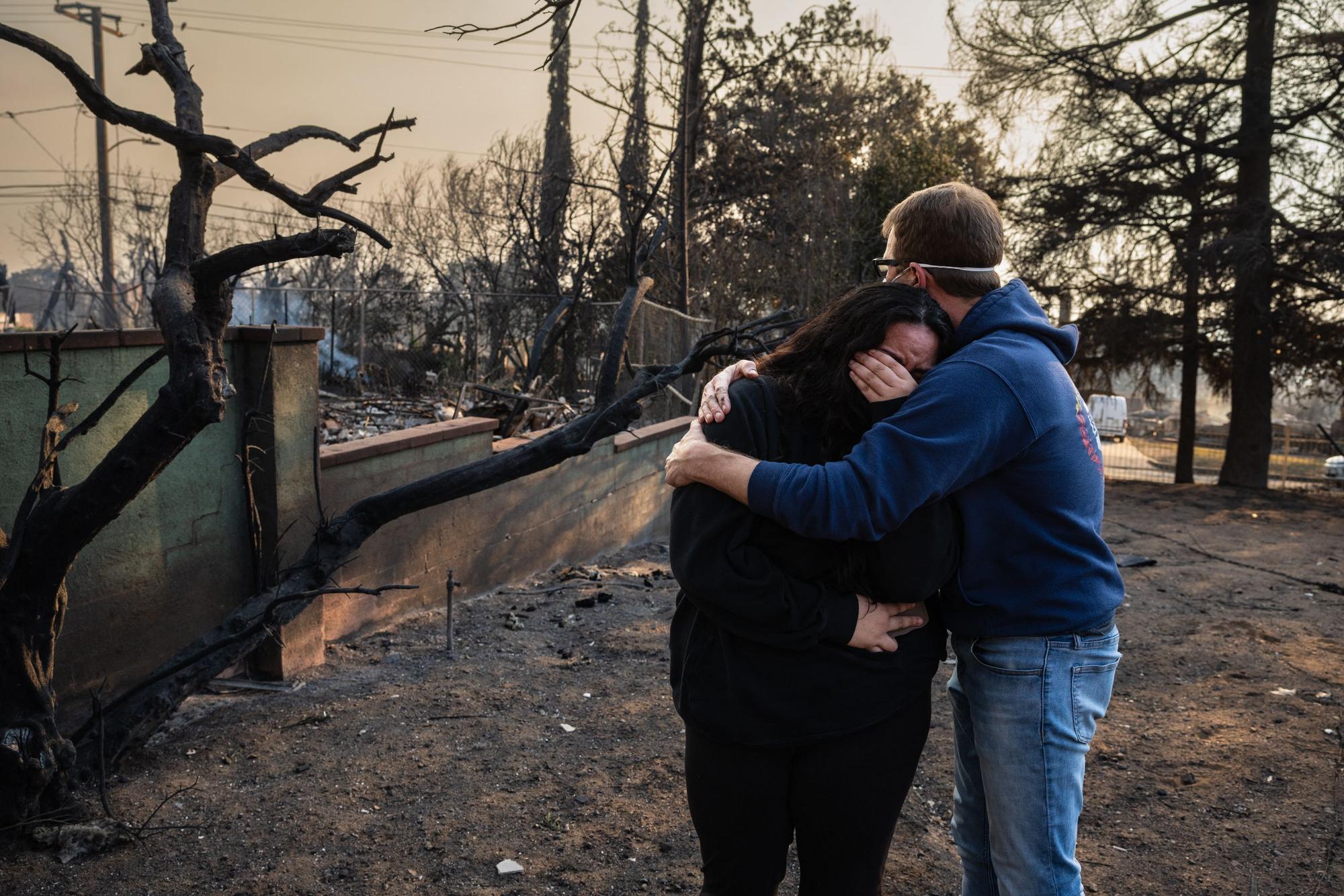 Ein Mann tröstet seine Tochter in den verkohlten Ruinen ihres Hauses, das im Eaton Fire in Altadena, Kalifornien, am 9. Januar 2025 verbrannt ist.