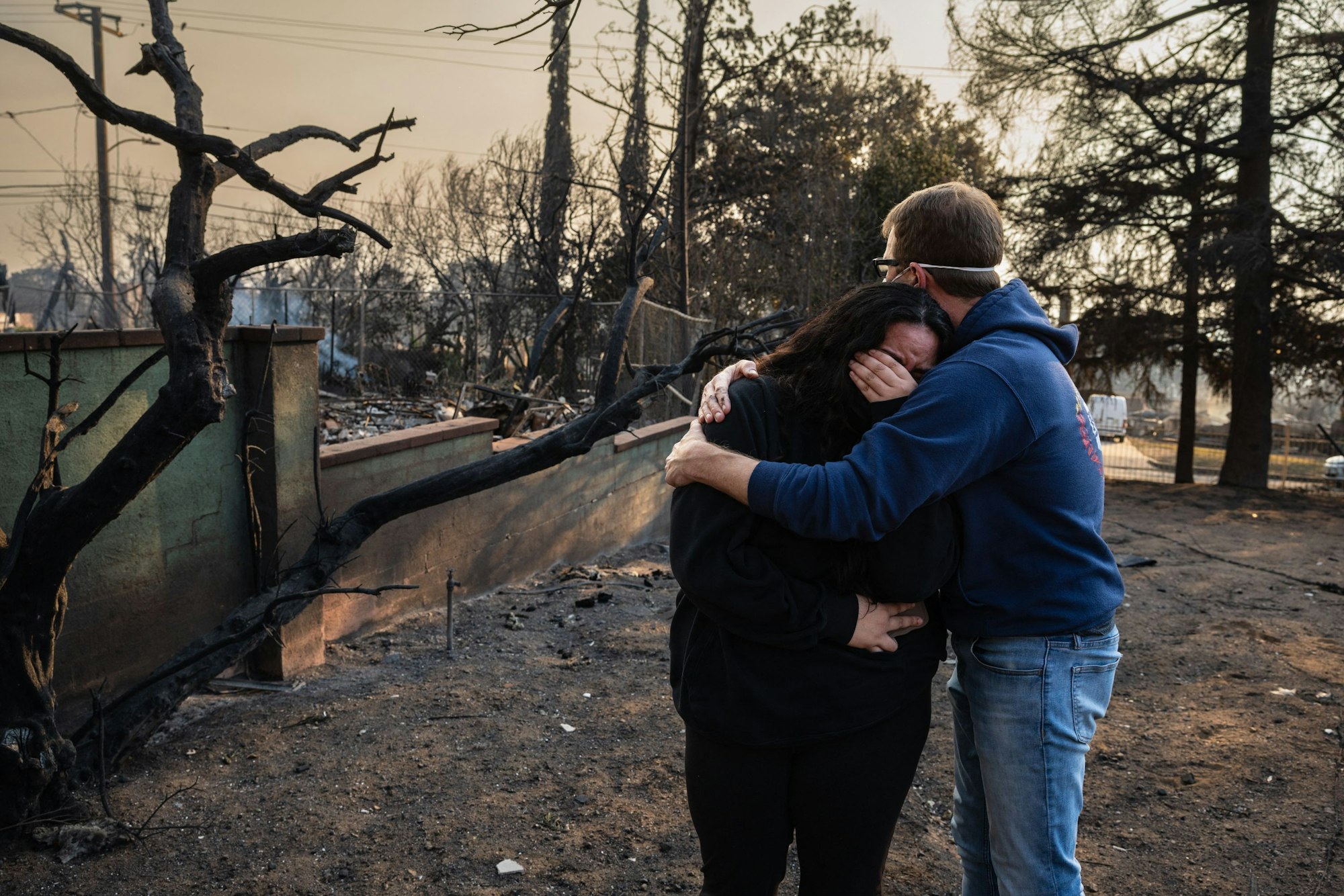Ein Mann tröstet seine Tochter in den verkohlten Ruinen ihres Hauses, das im Eaton Fire in Altadena, Kalifornien, am 9. Januar 2025 verbrannt ist.
