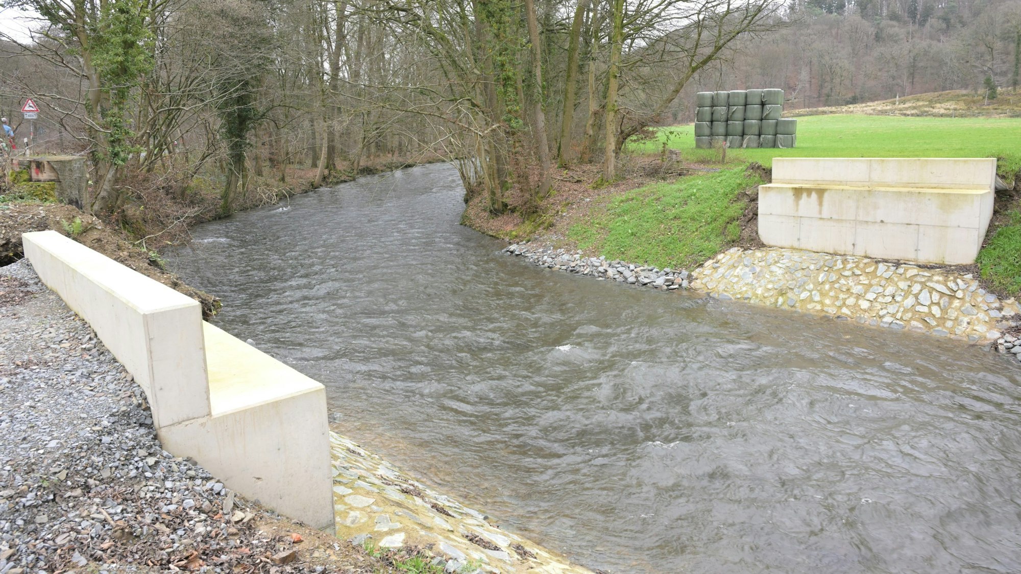 Ein Fluss, rechts und links neu gebaute Betonpfeiler, die Brücke dazwischen fehlt.