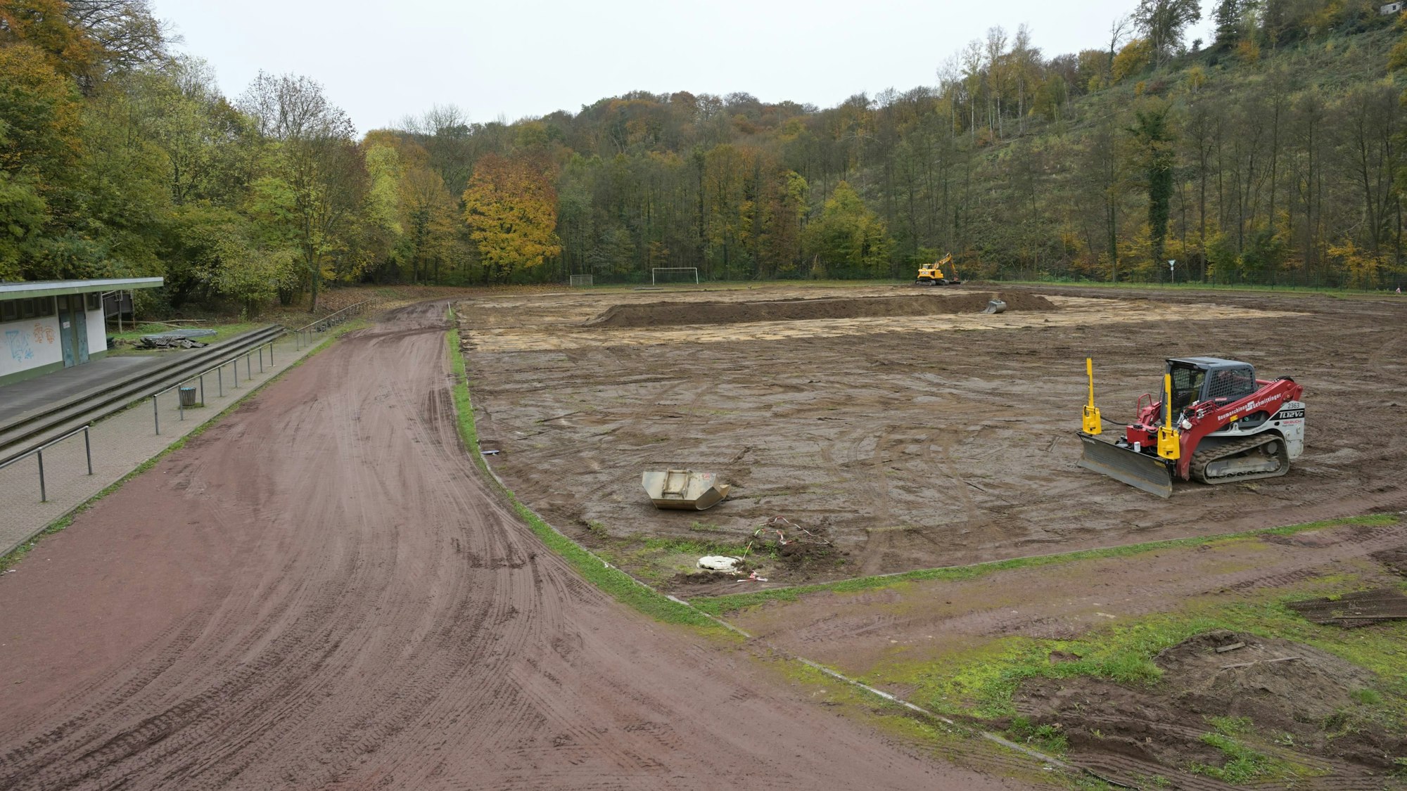 Ein Sportplatz wird umgebaut. Auf der ehemaligen Rasenfläche steht ein Bagger.
