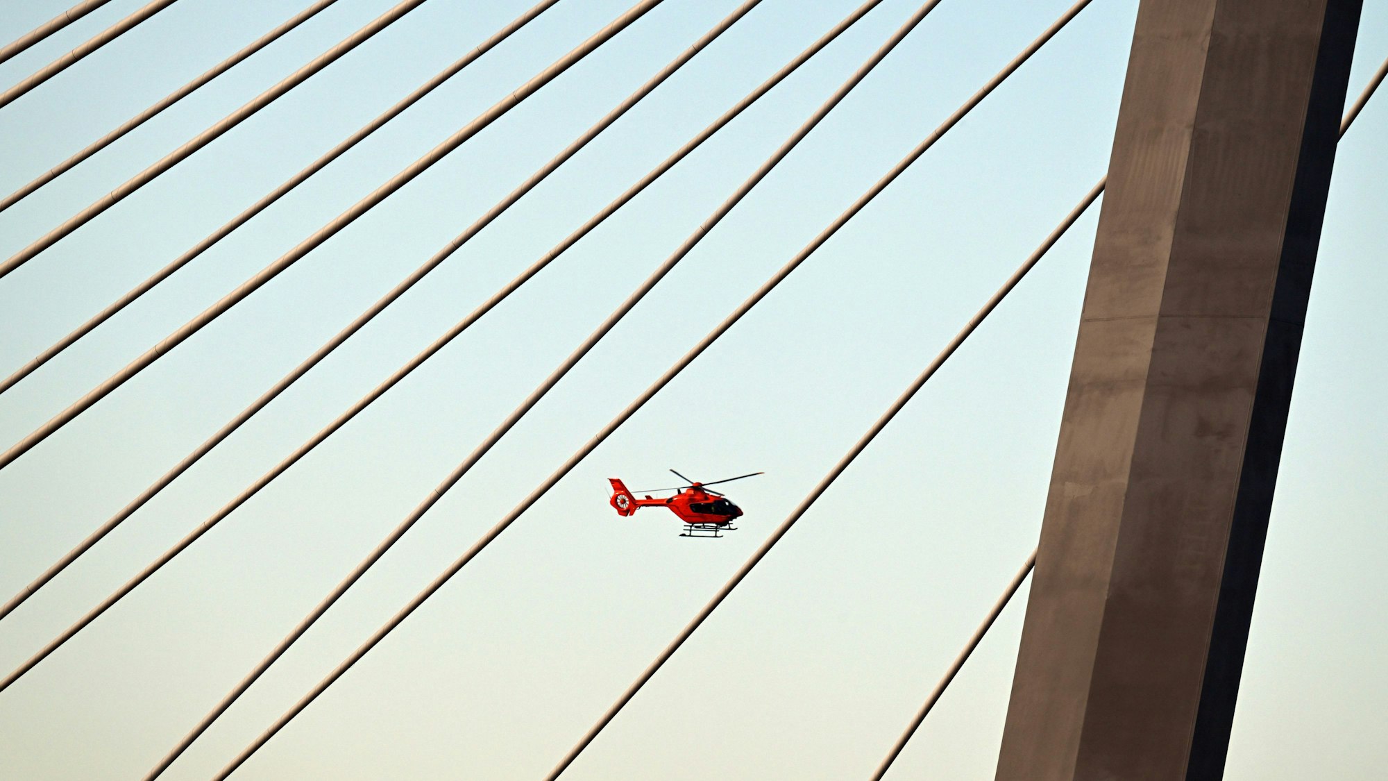 Ein Hubschrauber fliegt über einem Pylonen der Leverkusener Brücke.