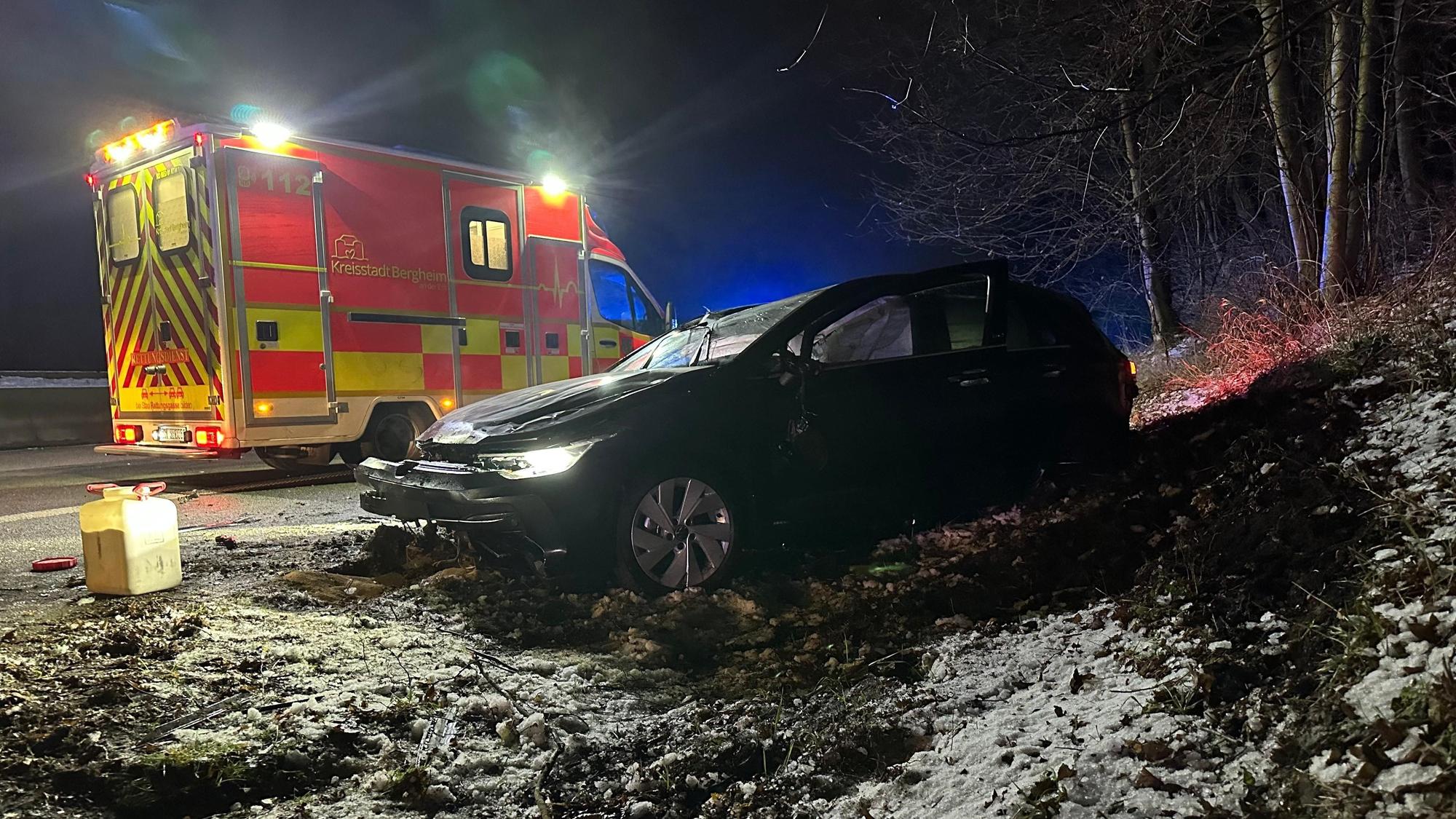 Ein zerstörtes Auto steht in einem Graben, dahinter steht ein Rettungswagen.