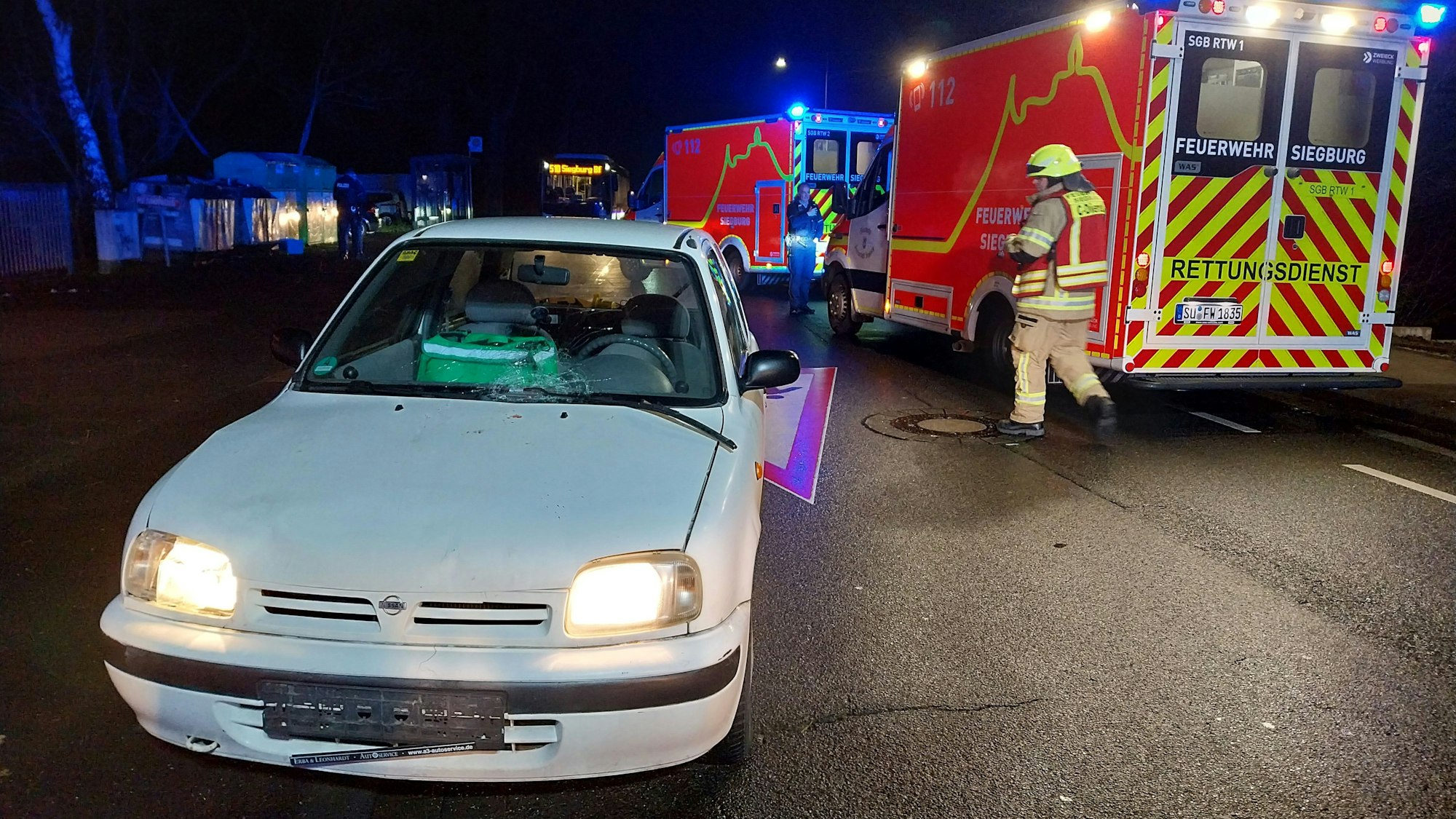 Ein beschädigtes Auto steht vor zwei Rettungswagen.