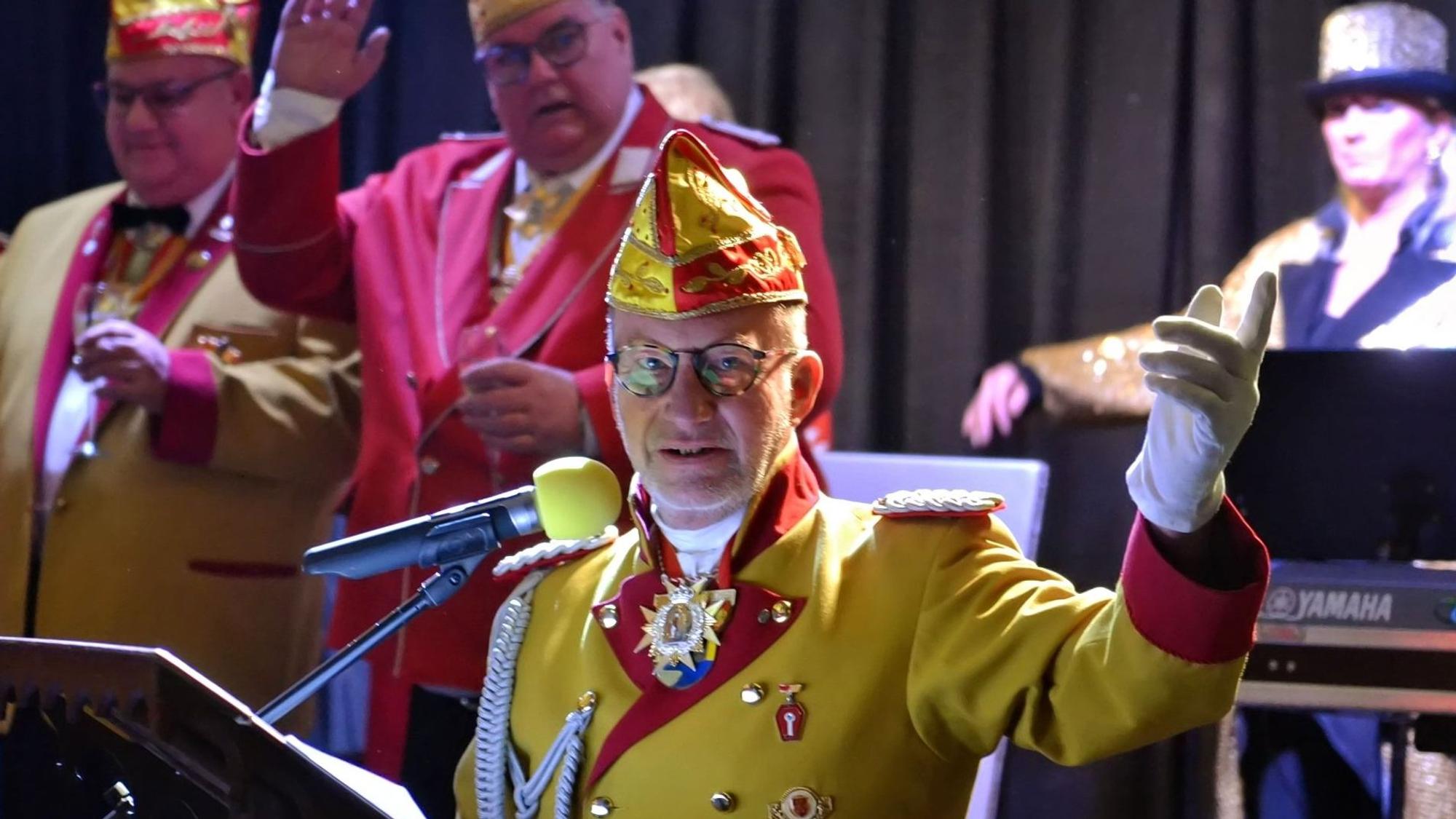 Michael Neugebauer steht in einer Karnevals-Uniform am Mikrofon.