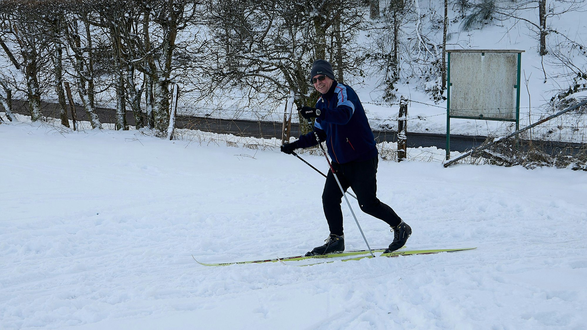 Ein Mann fährt in der Eifel auf Langlaufskiern durch den Schnee.