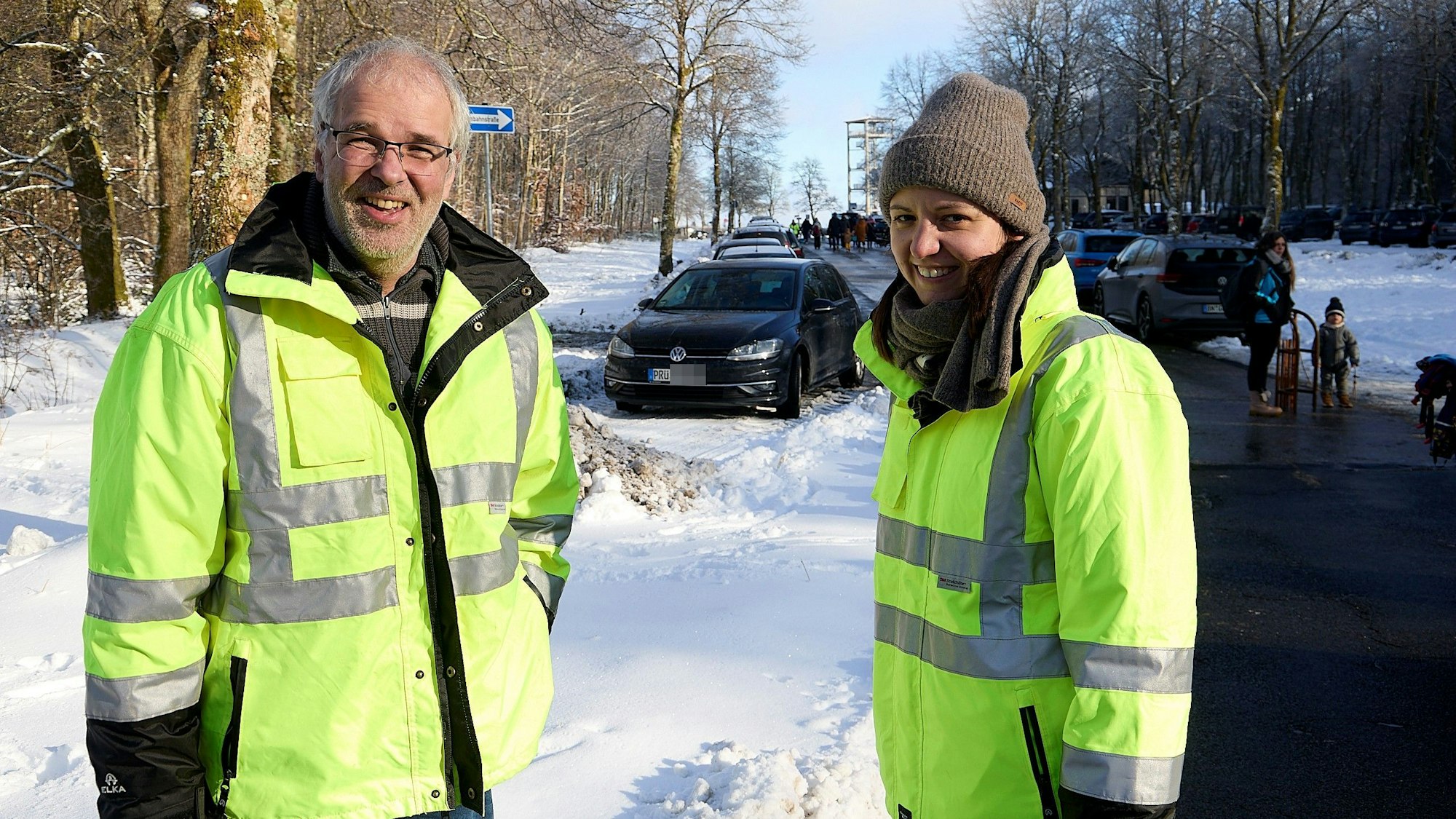 Ein Mann und eine Frau stehen in neongelben Warnjacken auf dem Hauptparkplatz am Weißen Stein in Hellenthal-Udenbreth.