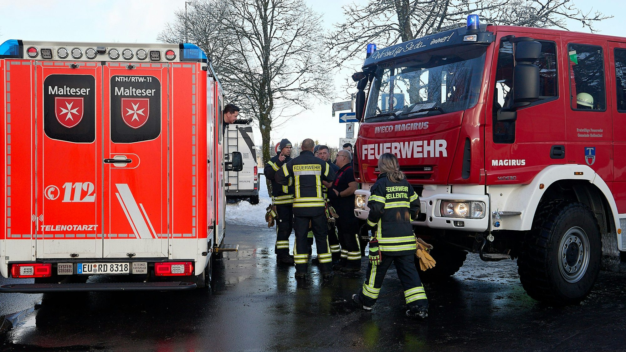 Ein Feuerwehrfahrzeug und ein Rettungswagen stehen am Weißen Stein in Udenbreth. Einige Feuerwehrleute in Einsatzkleidung stehen daneben.