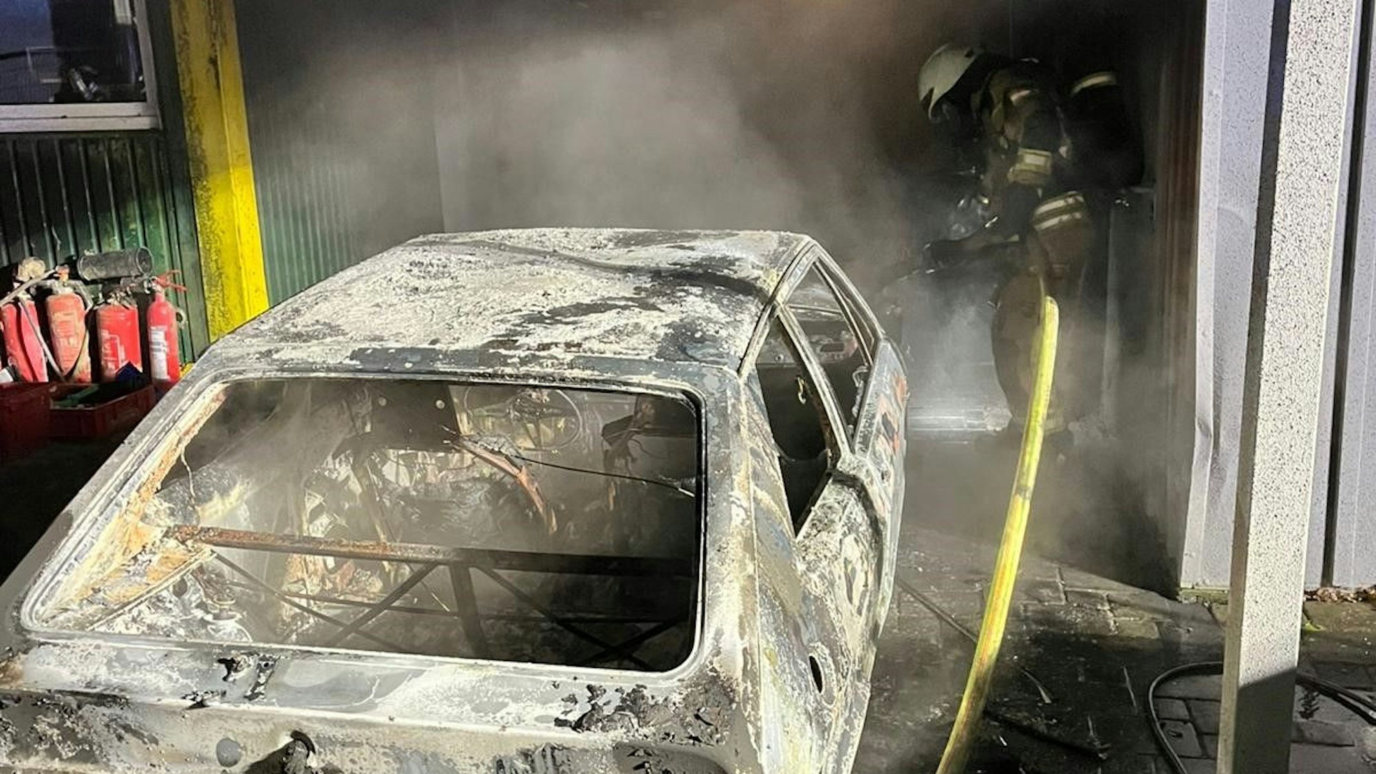 Ein Autowrack, dahinter ein Feuerwehrmann.