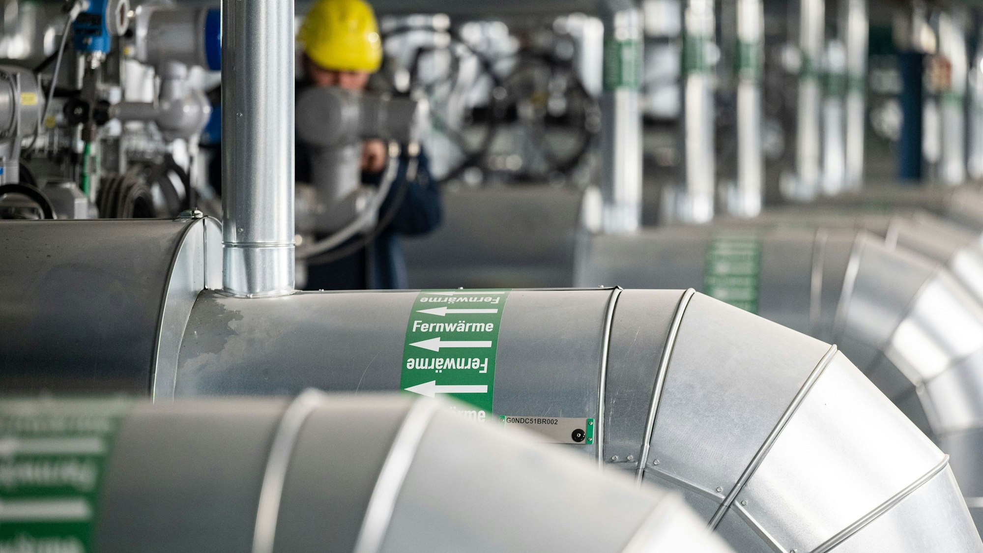 Ein Mann kontrolliert die Fernwärmeverteilerstation eines Heizkraftwerks.