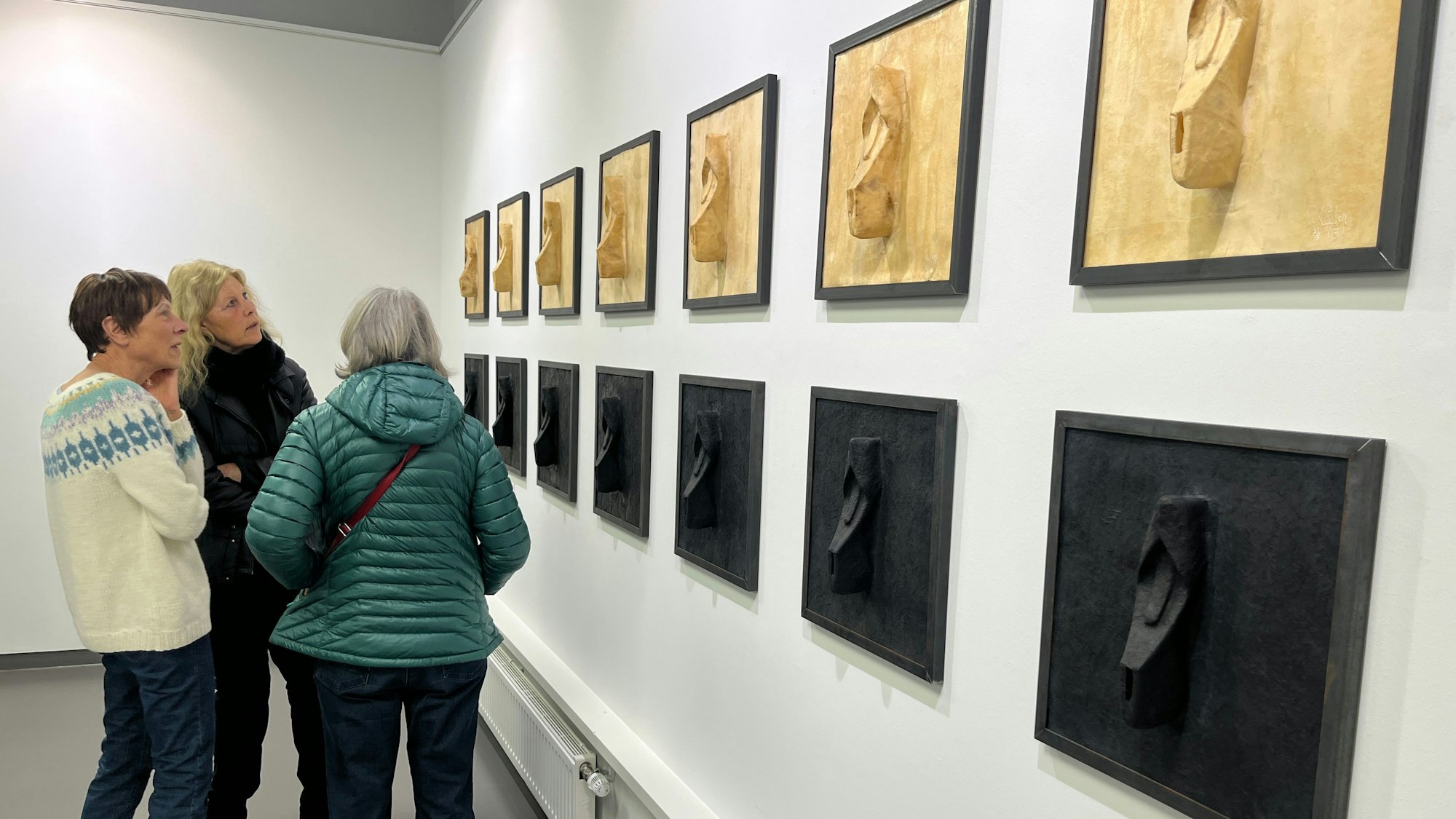 Besucher einer Ausstellung schauen sich Kunstwerke an.