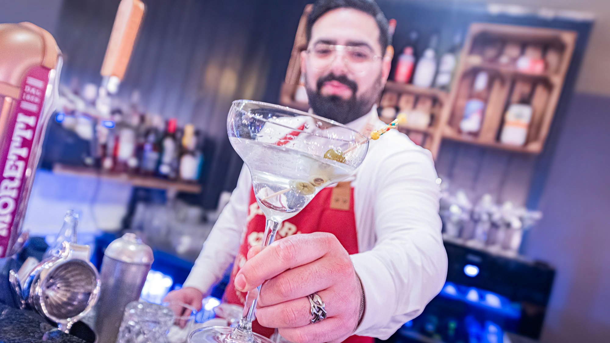 Barkeeper im Bellini hält ein Cocktailglas hoch.