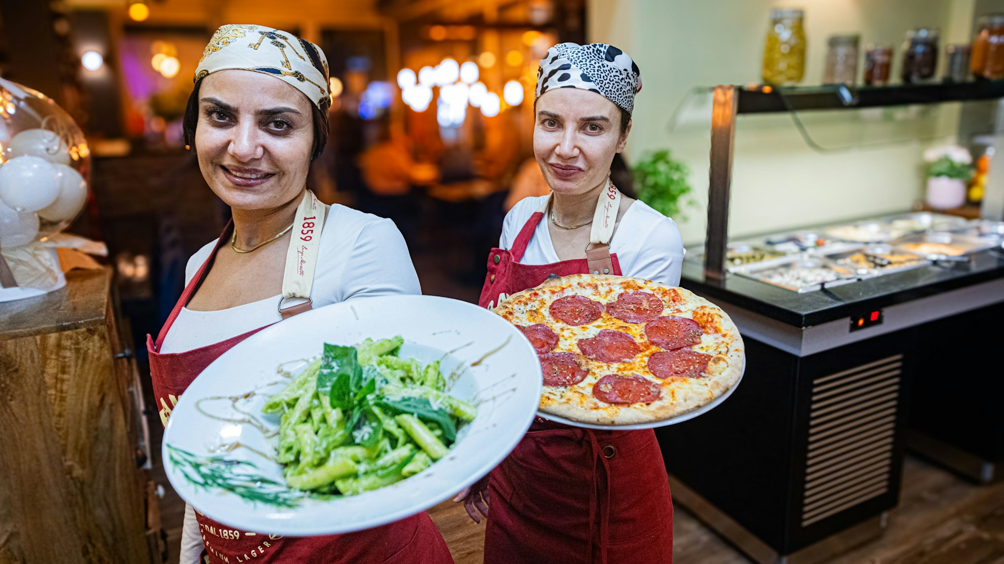 Neslihan Aksu (links ) und eine Mitarbeiterin servieren Speisen.
