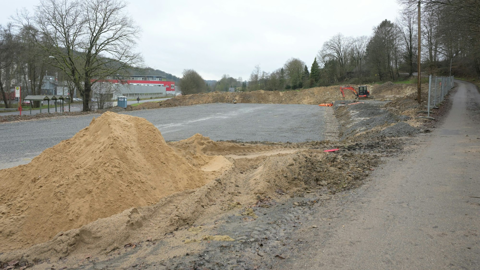 Ein Gelände ist planiert, davor liegt ein großer Sandhaufen.