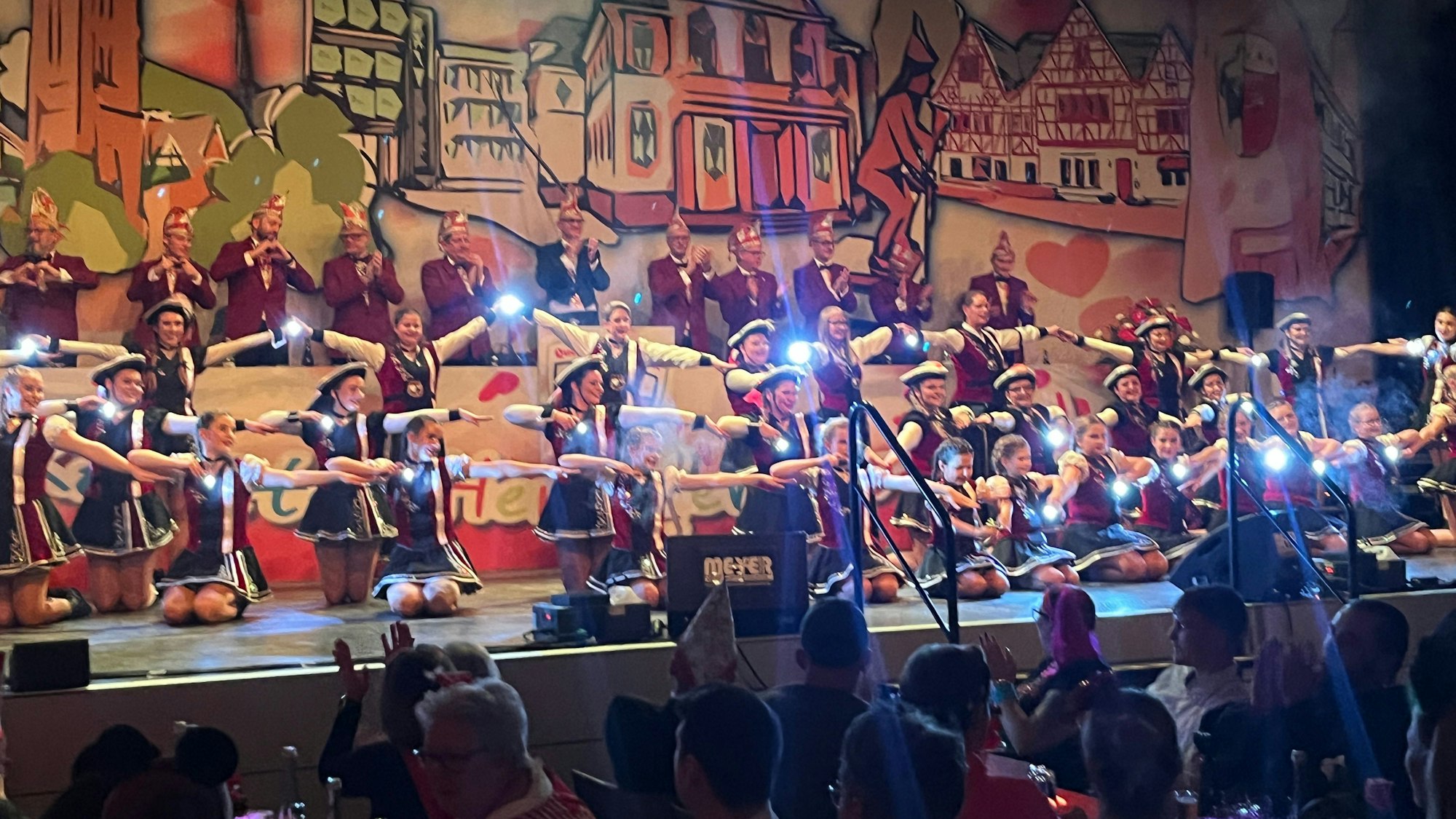 Junge Tänzerinnen leuchten mit Taschenlampen in Richtung Publikum.