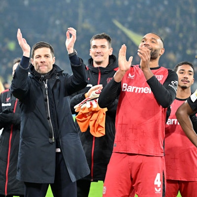 Leverkusens Edmond Tapsoba (l-r), Trainer Xabi Alonso und Jonathan Tah feiern den Sieg.