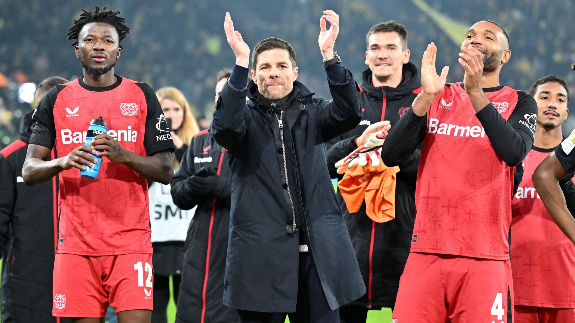 Leverkusens Edmond Tapsoba (l-r), Trainer Xabi Alonso und Jonathan Tah feiern den Sieg.