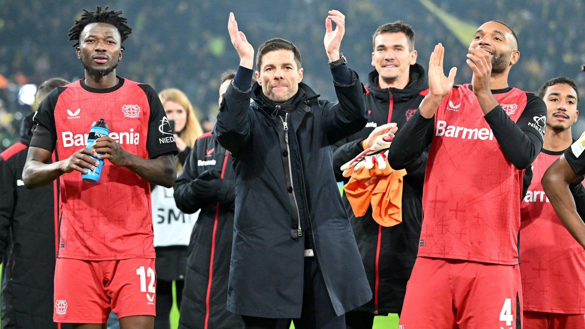 Leverkusens Edmond Tapsoba (l-r), Trainer Xabi Alonso und Jonathan Tah feiern den Sieg.