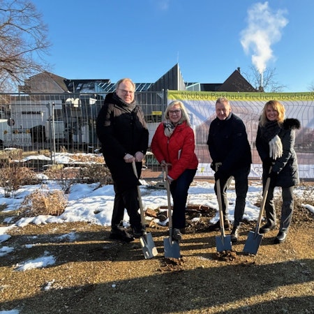 Auf dem Bild sind zwei Frauen und zwei Männer mit Spaten zu sehen, die symbolisch etwas Erde schaufeln.