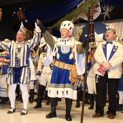 Tollitäten stehen auf eine Bühne.