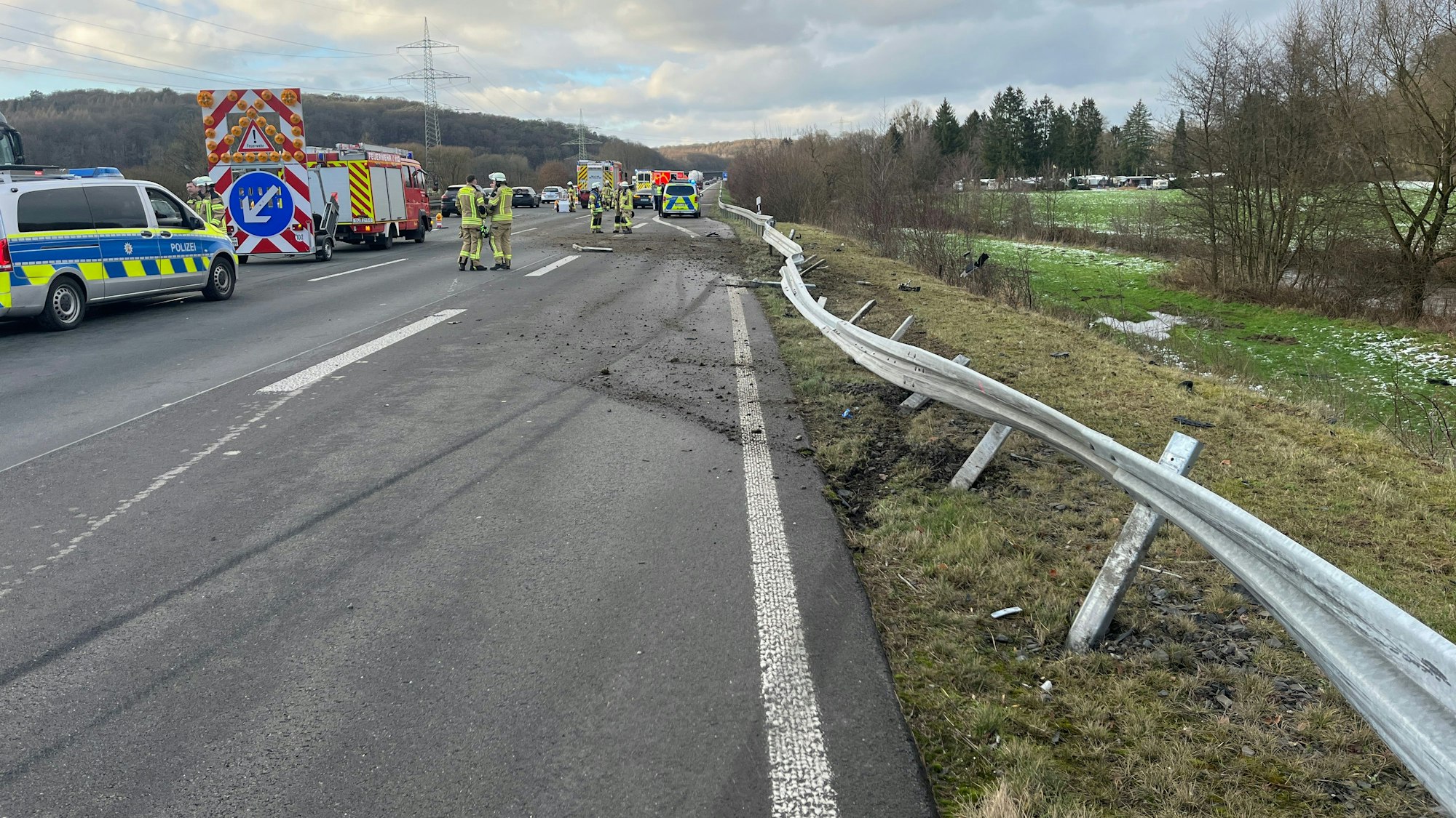 Deutliche Bremsspuren auf dem rechten Fahrstreifen der Autobahn 3 kurz hinter der Raststätte Sülztal, die Leitplanke ist eingedrückt, Erde aufgewühlt. Polizei und Feuerwehr stehen an der Unfallstelle.