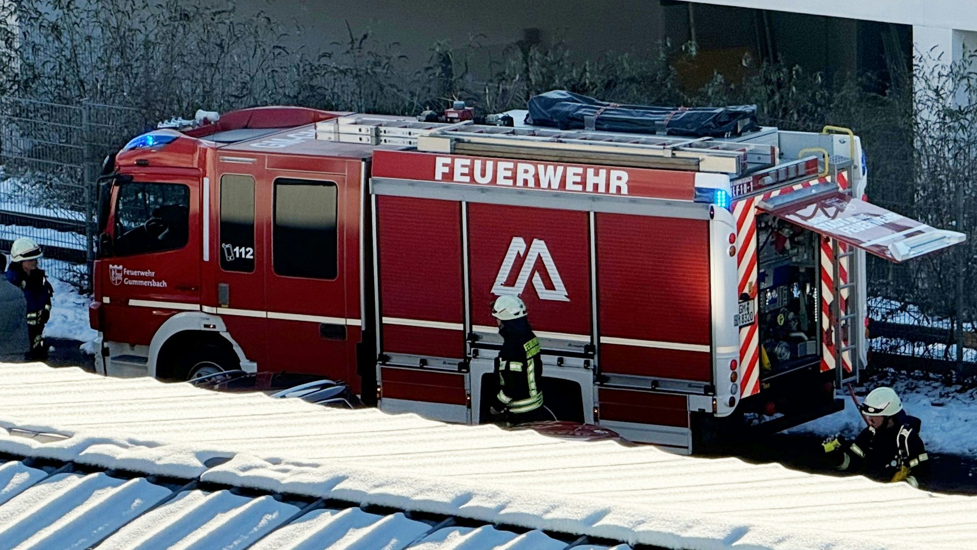 Ein Feuerwehrauto und Einsatzkräfte stehen auf einer Parkfläche.