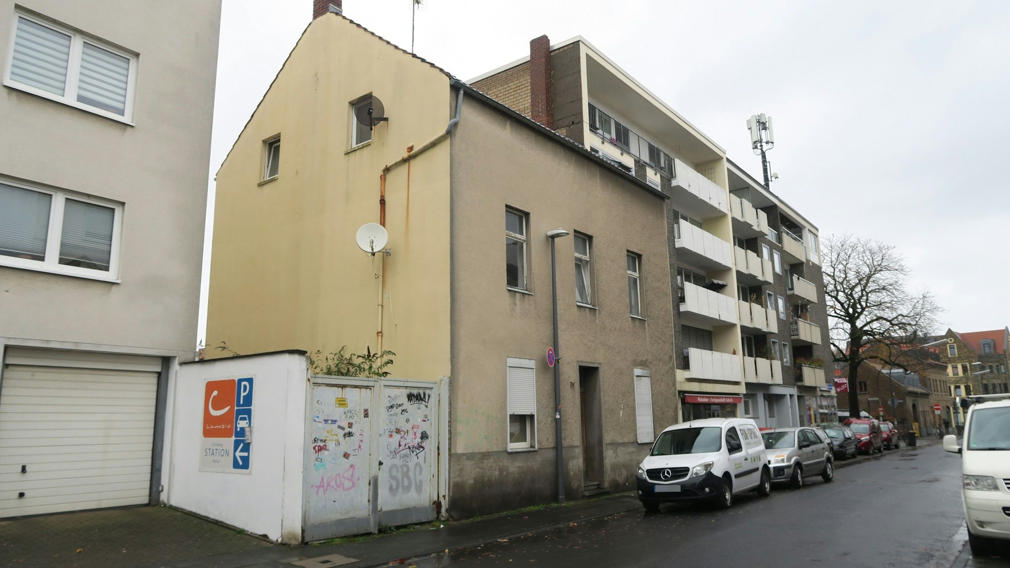 Ein beiges dreistöckiges Haus steht deutlich näher an der Straße als die Häuser neben ihm.