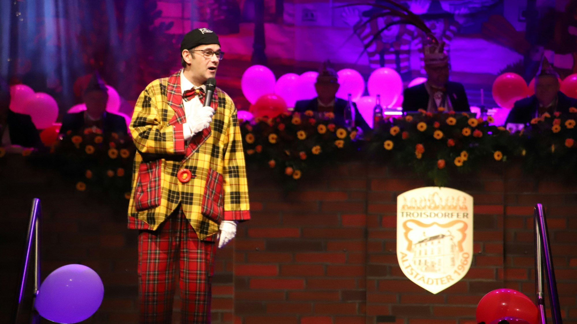 Ein Redner steht auf der Bühne bei einer Karnevalsveranstaltung.