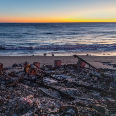 Ein Feuerwehrmann geht durch verbrannte Ruinen eines Hauses am Strand von Kalifornien.