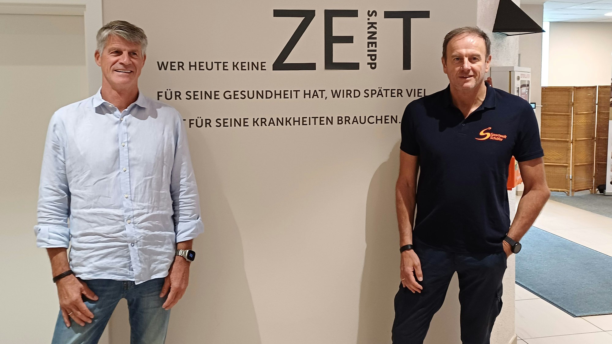 Jochen Förster und Franz-Peter Schäfer posieren vor einer Wand, auf der ein Spruch von Sebastian Kneipp steht.