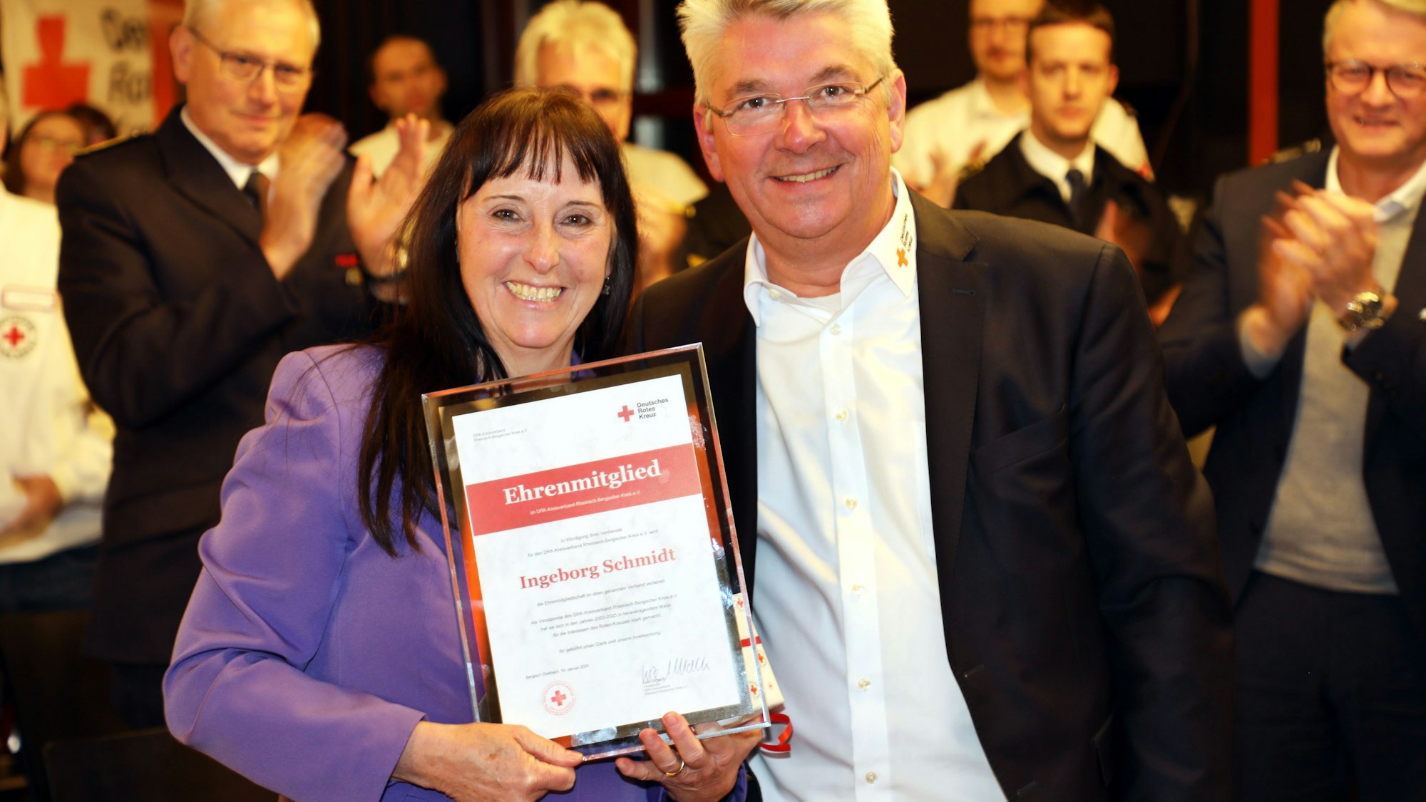 Ingeborg Schmidt hält eine Ehrenmitgliedsurkunde und steht neben ihrem Nachfolger an der DRK-Kreisspitze, Lutz Urbach.