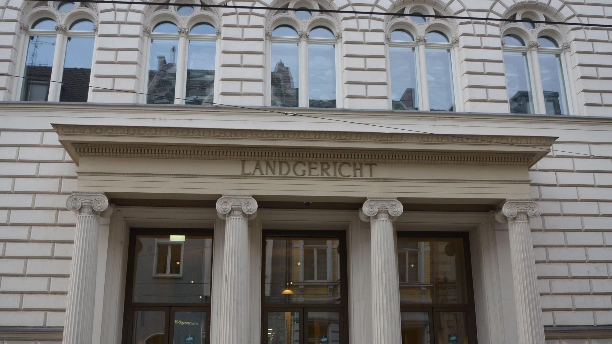 Das Foto zeigt den Eingang des Landgerichts, ein helles Gebäude mit Rundbogenfenstern und Säulen vor der Tür.