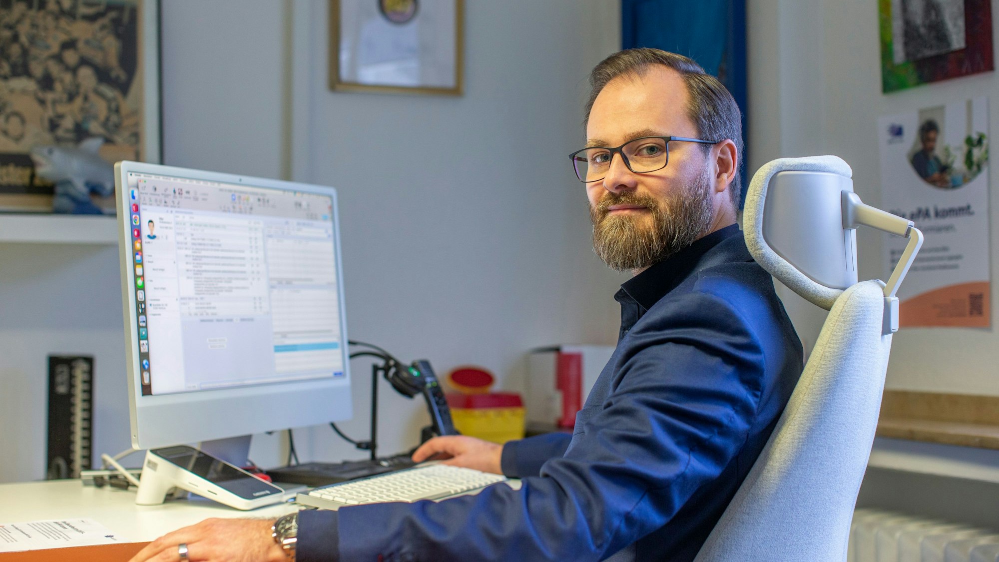 Dr. Oliver Pottkämper sitzt auf einem Stuhl vor einem Bildschirm.