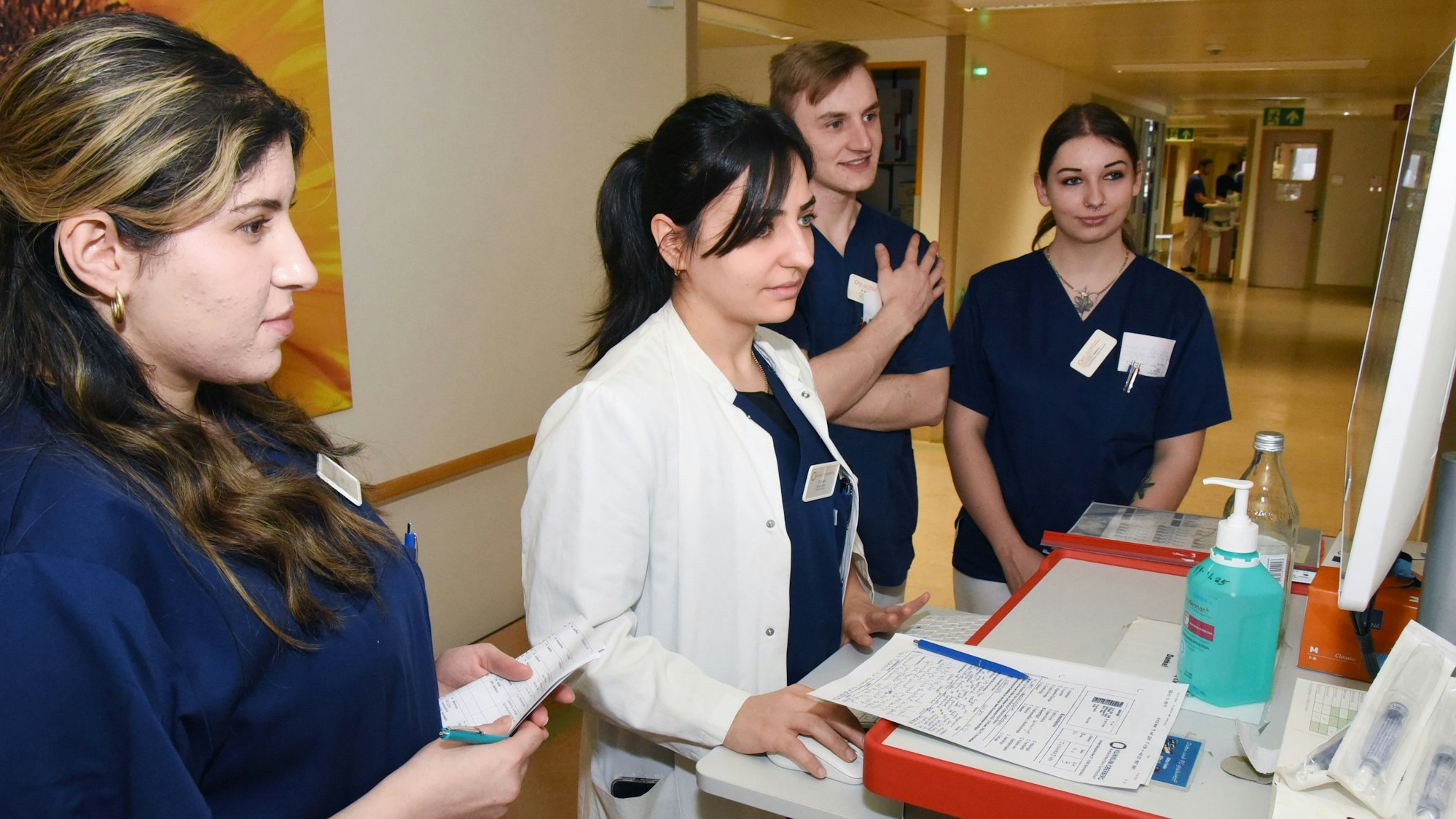 Pflegeschülerinne und -schüler haben sich vor einem Monitor versammelt.