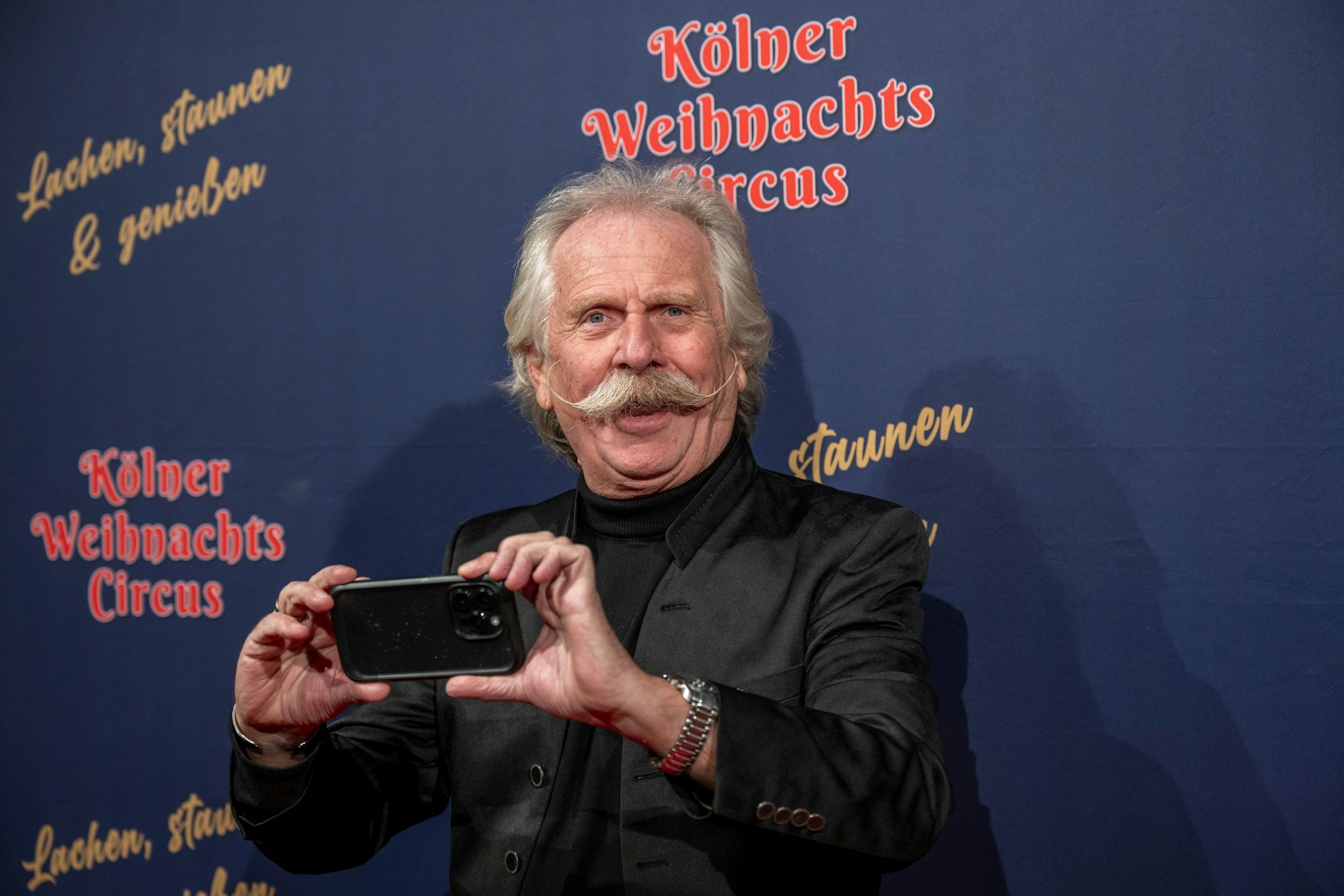 Ein Mann hält ein Handy und lacht.