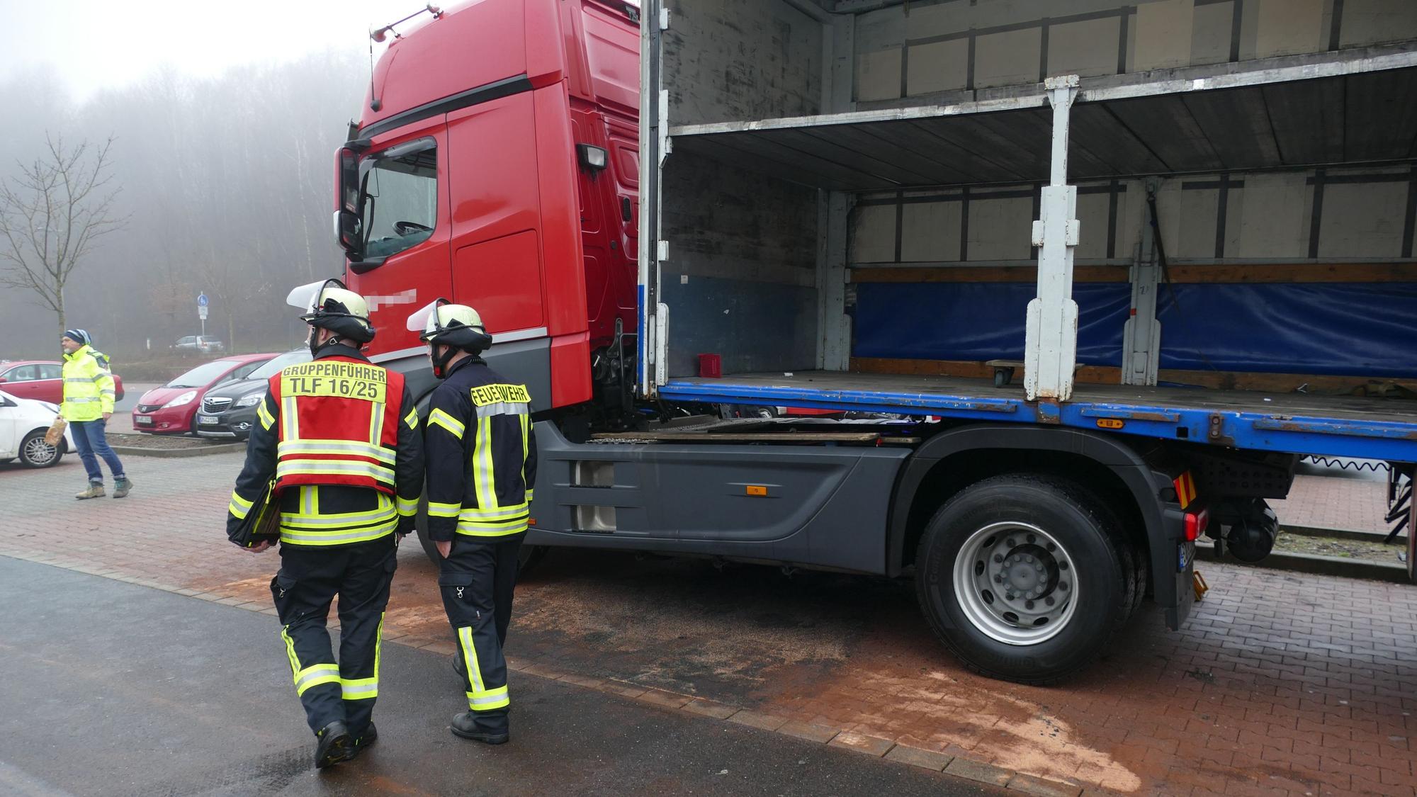 Feuerwehrleute stehen vor der abgestreuten Diesel-Pfütze des Lkws.