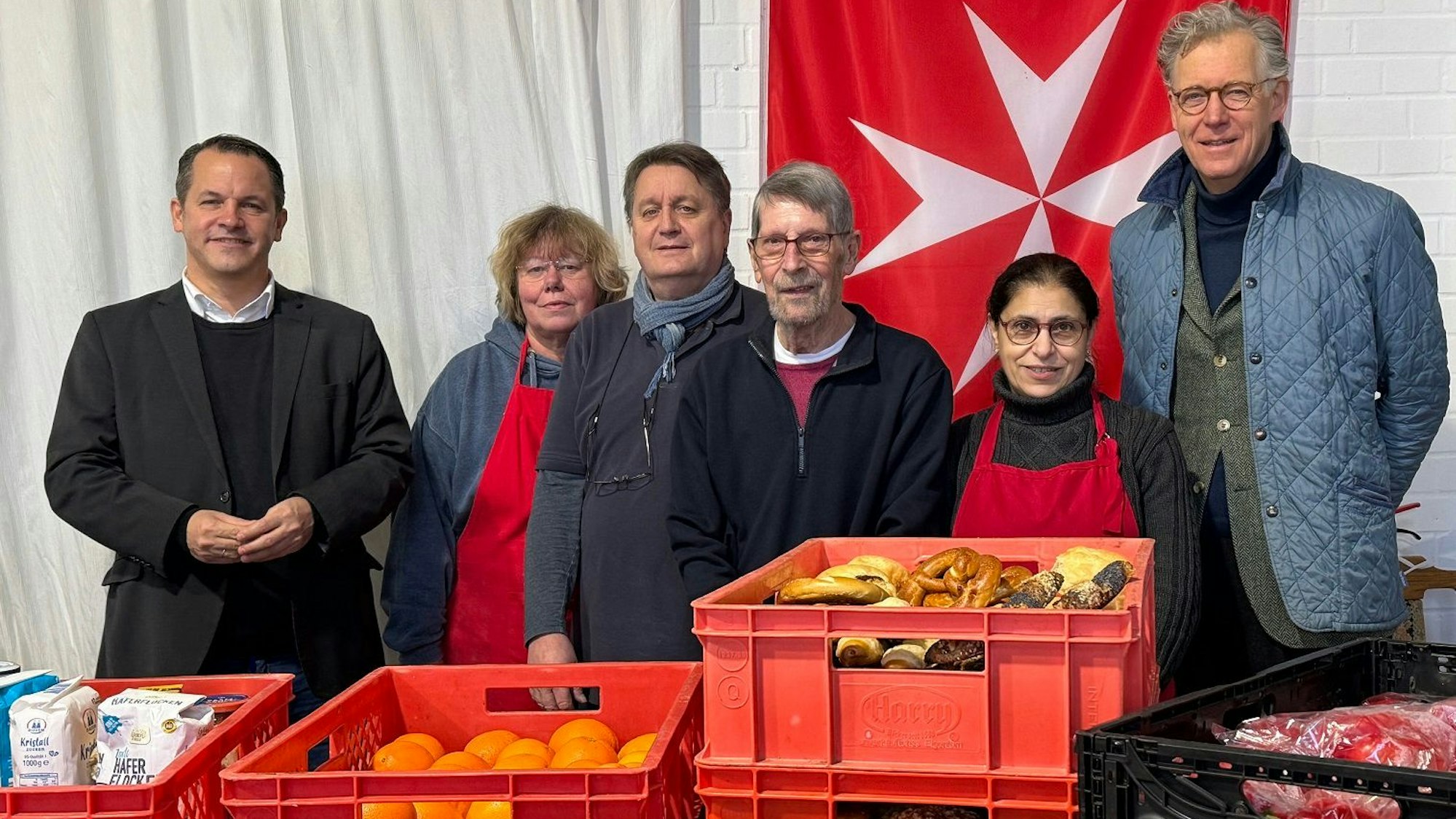 Menschen stehen hinter einem Tisch, auf dem Lebensmittel stehen.