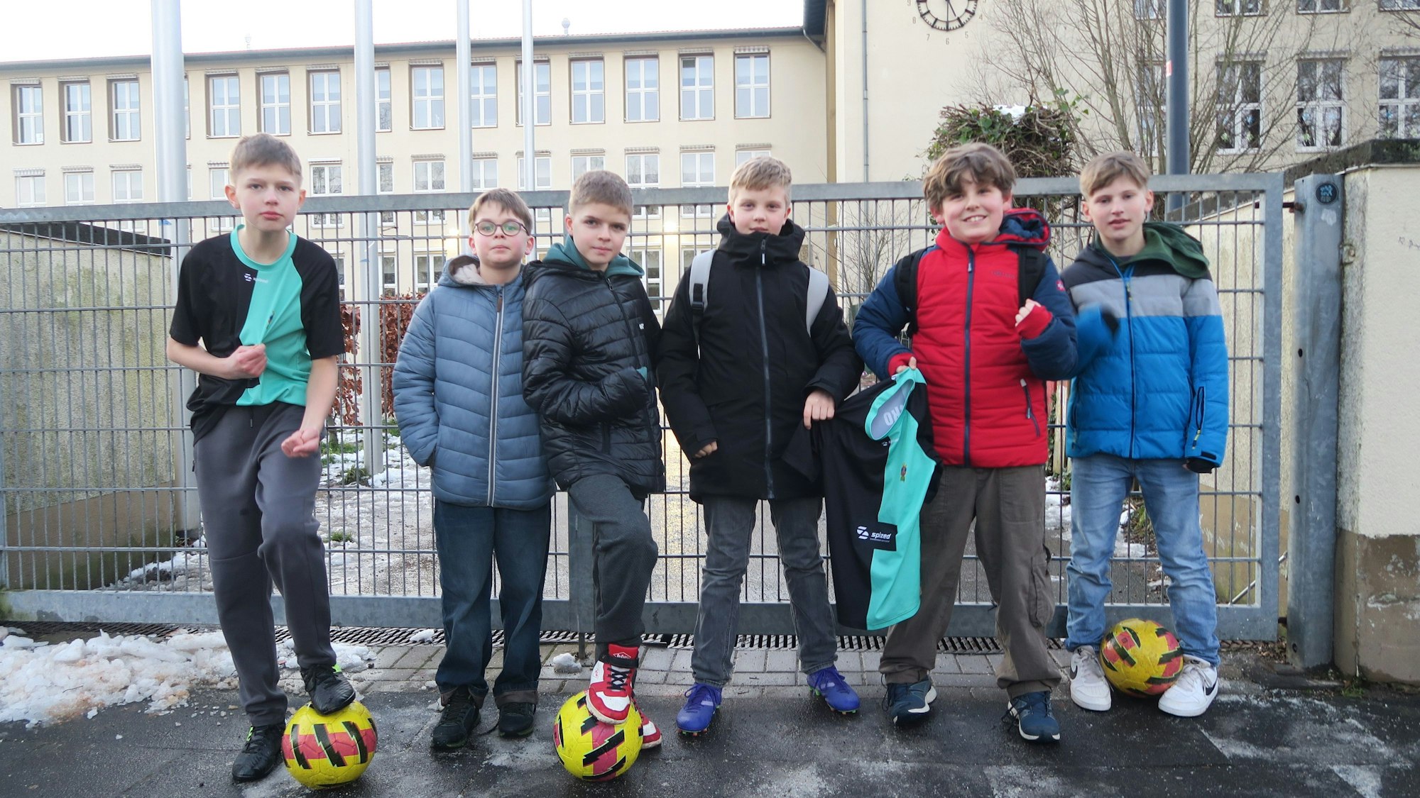 Sechs Jungs stehen vor einem verschlossenen Schulhof-Tor.