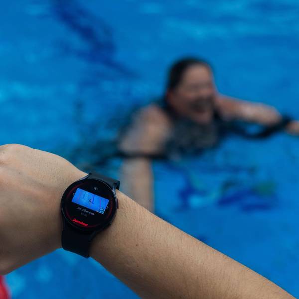 Ein Bademeister trägt eine Smartwatch am Handgelenk, die ein Warnsignal zeigt.