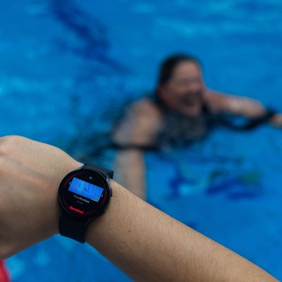 Ein Bademeister trägt eine Smartwatch am Handgelenk, die ein Warnsignal zeigt.
