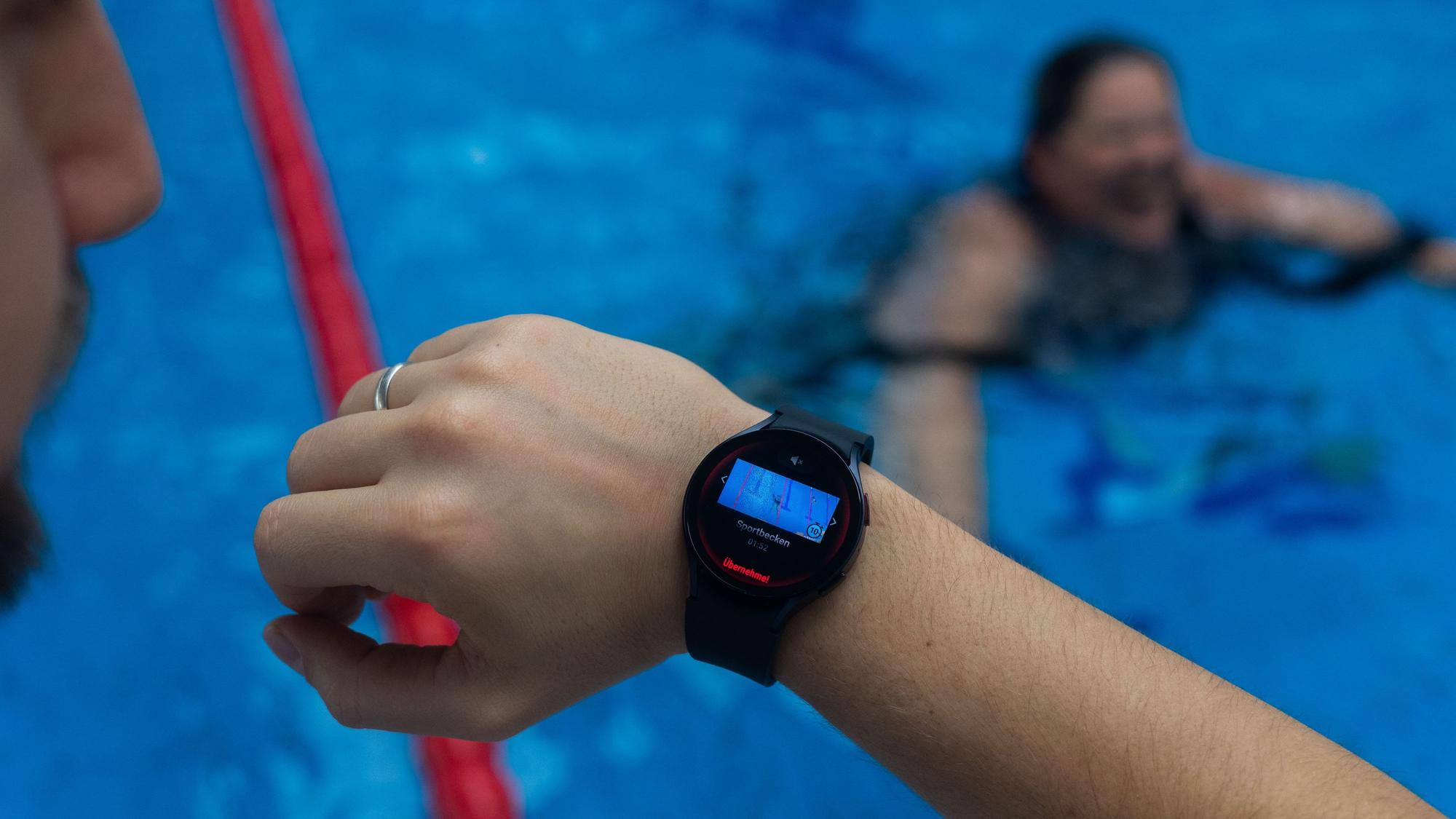 Ein Bademeister trägt eine Smartwatch am Handgelenk, die ein Warnsignal zeigt.